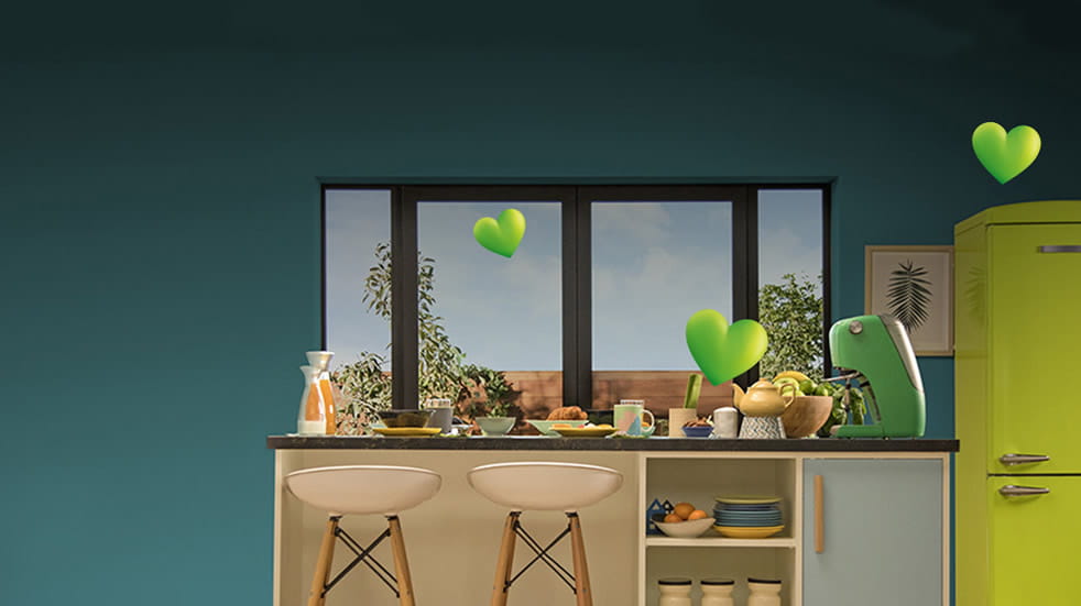 Interior kitchen setting, predominantly green coloured, looking towards a closed window. Small breakfast bar with two stools, a large green fridge/freezer to the right-hand side of the image. Three small green hearts float in the air above the breakfast bar and fridge. 
